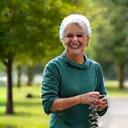 Active woman, early 50s, mid-stride on a walking trail.